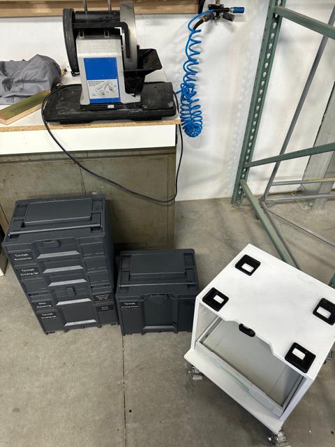Disassembled sharpening station components - Sortainer stacks, the custom white rolling cart base, and the Tormek sharpener on the bench