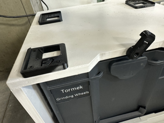 Close-up of labeled 3D-printed brackets and the locking catch on top of the cabinet, above a Sortainer drawer labeled Tormek Grinding Wheels