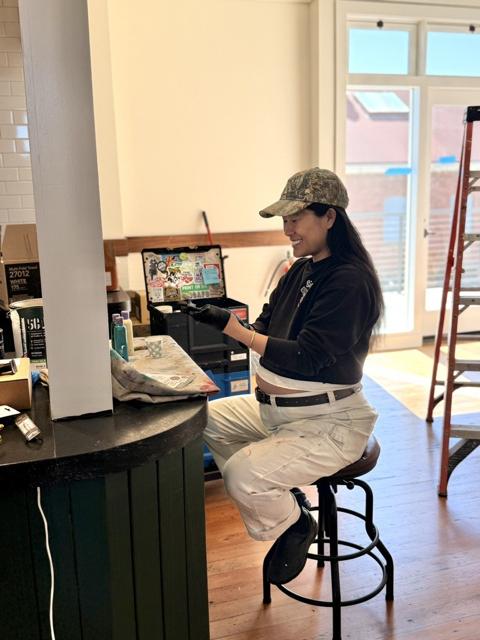 Signs by Meng smiling while working, with a Systainer stack covered in stickers from friends and fans visible in the background