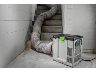 Festool SYS-AIR at the foot of a bare concrete stairwell with its 200 mm air supply hose running up the stairs