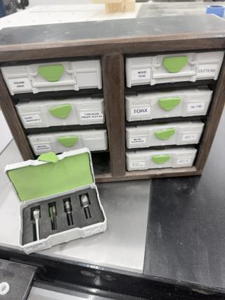 A Systainer³ XXS labeled COUNTERSINK BITS open on the bench in front of the cabinet, four countersink bits held in a cut foam insert with a green foam lid liner above