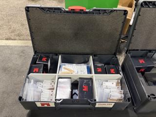 Anthracite systainer open on a table, its foam-lined lid raised, the base filled with white divider trays holding labelled wood plug sample cards in hickory, cherry, ash, red oak, maple and poplar alongside black boxes of Castle screws