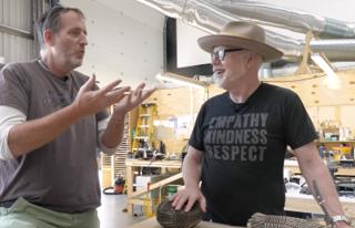 Art director Tim Browning explaining Rocky's alien models to Adam Savage in the Project Hail Mary prop shop, with two Light Grey systainers stacked on the lower shelf of a wooden workbench in the background